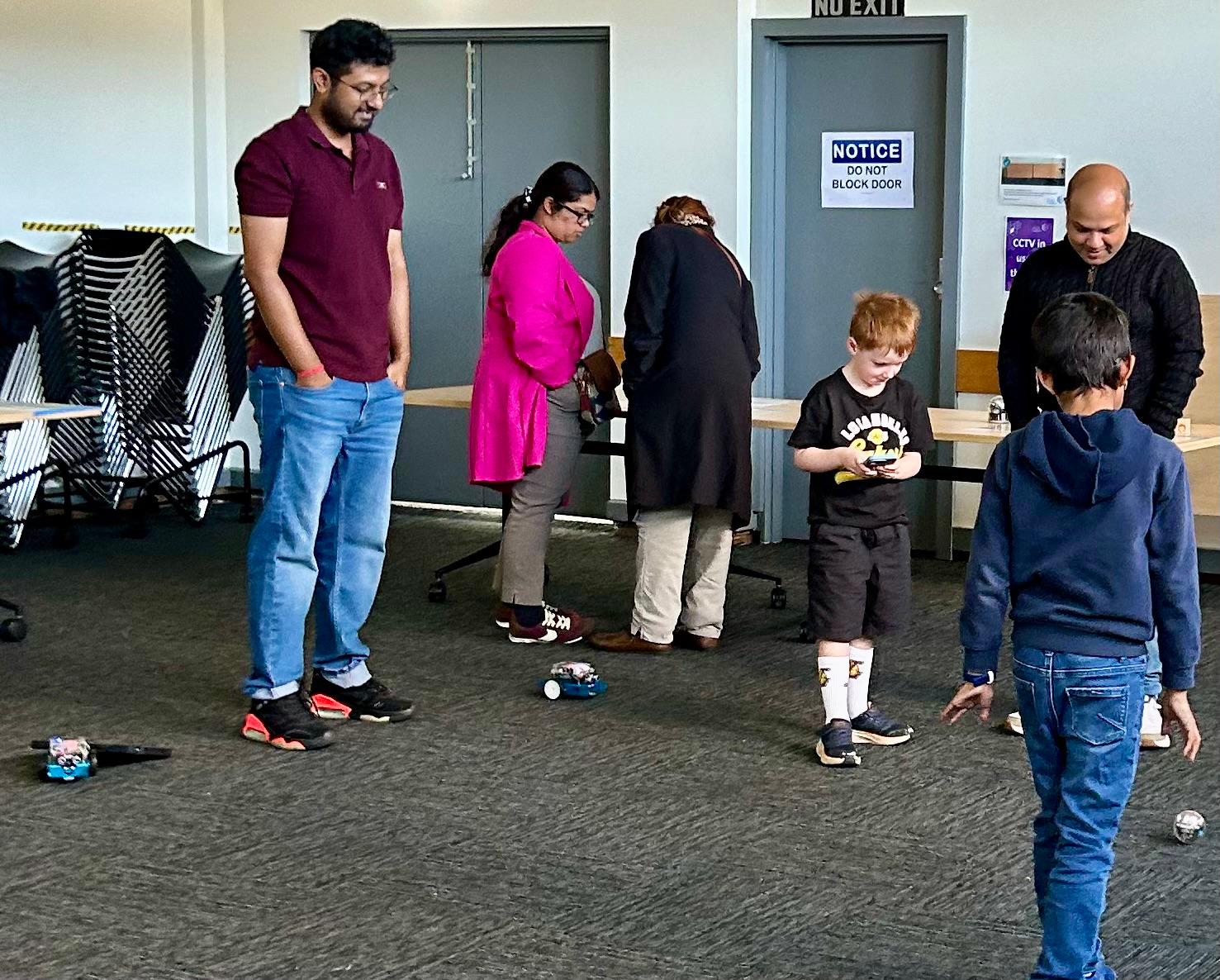 Children using handheld controllers to explore robots with adults at Corio Library